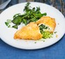 Breaded chicken kiev on a plate filled with wild garlic butter, served with salad