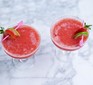 Two glasses of frozen strawberry daiquiri, with a garnish