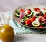 Greek-style salad dressing in a small jar next to a Greek salad