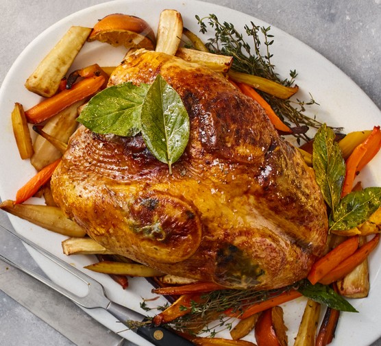 Roast turkey crown on a plate with roast carrots, parsnips and thyme
