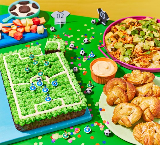 Football party spread with football pitch cake, nachos and football dip