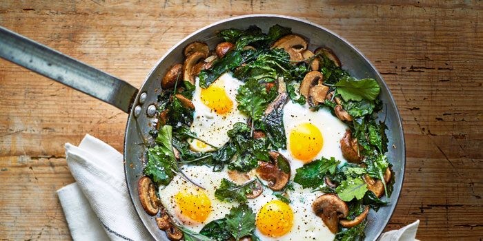Fried eggs, mushrooms and spinach in a frying pan