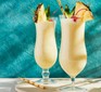 Pina colada cocktails in glasses with pineapple wedges