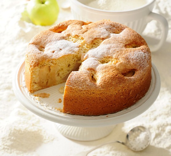 Polish apple cake on a stand, with slice taken out