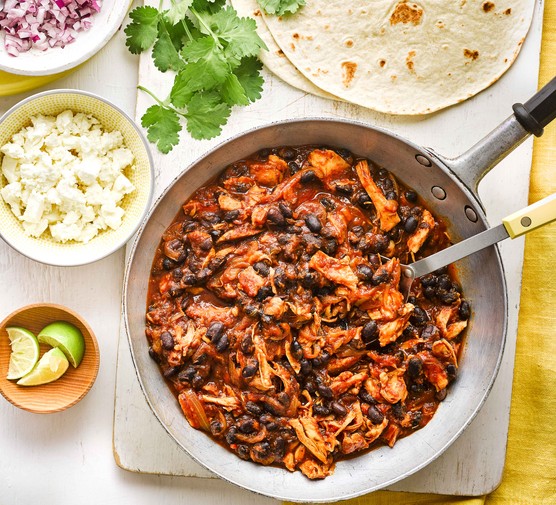Pan of pulled chicken and black beans with toppings