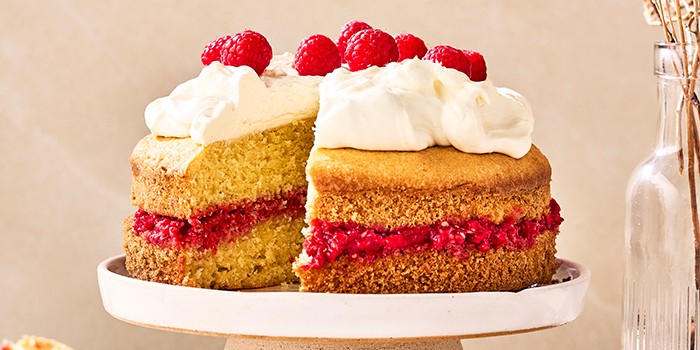 Victoria sponge cake topped with cream and raspberries