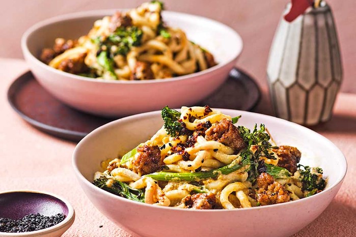 Two servings of tahini miso noodles with crispy broccoli & sausages